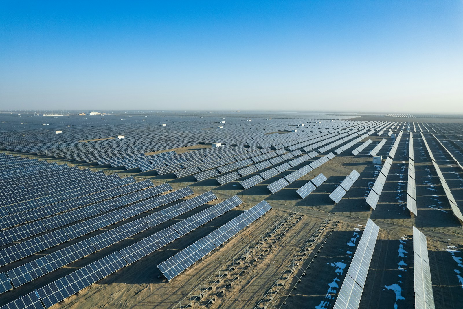 Aerial view of a vast desert solar farm — the Mohammed bin Rashid Al Maktoum Solar Park is built on terrain like this and powers Dubai's Hassyan desalination plant entirely