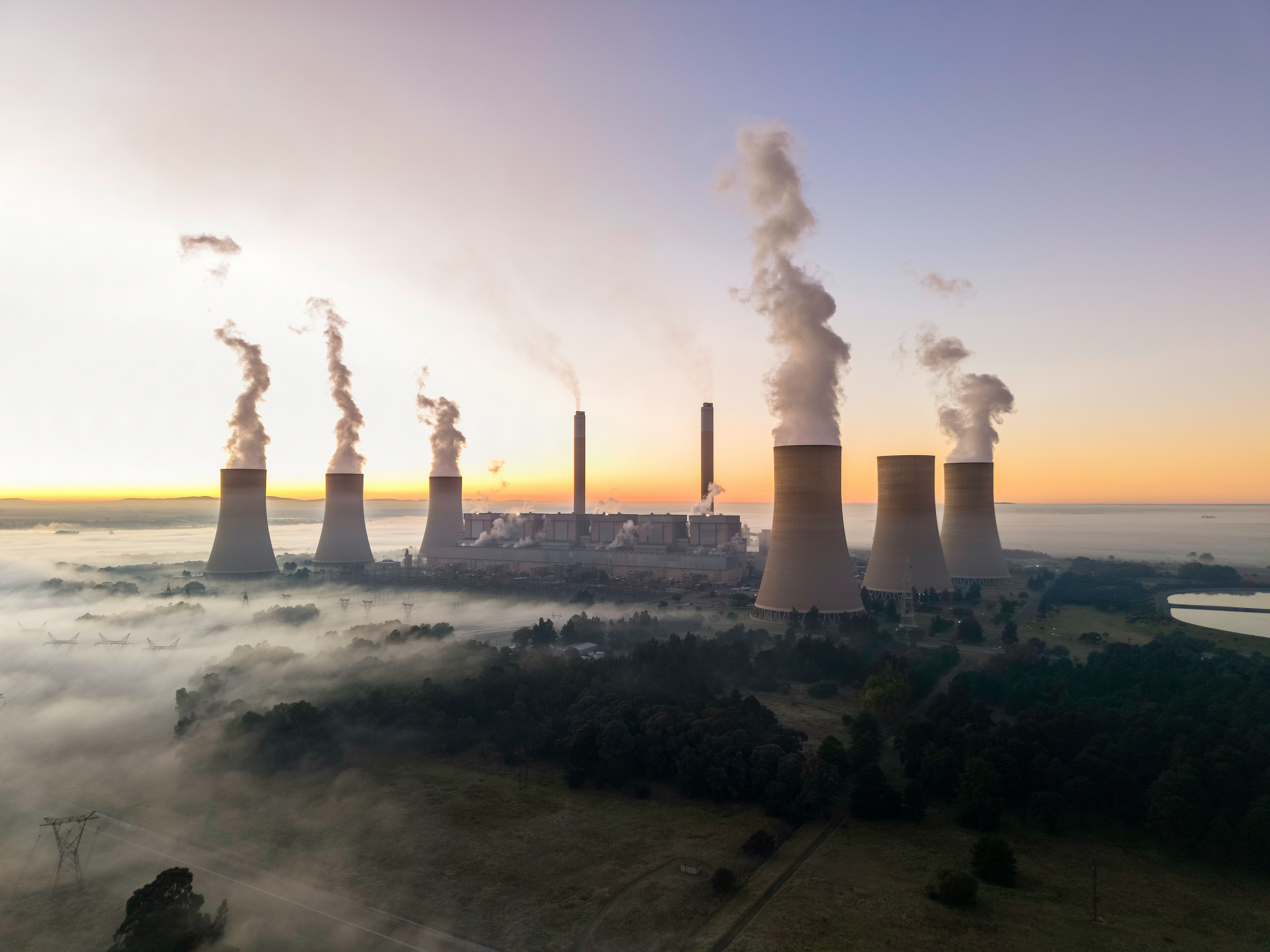 Large nuclear power plant with cooling towers rising against an industrial dusk sky, representing the scale of China's Tianwan facility and the global expansion of nuclear energy capacity